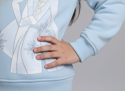 Light blue sweater with white floral design worn by a girl, on a gray background