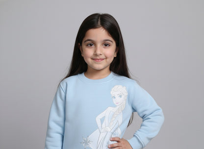 Young girl wearing a light blue sweatshirt with a frozen design on a gray background