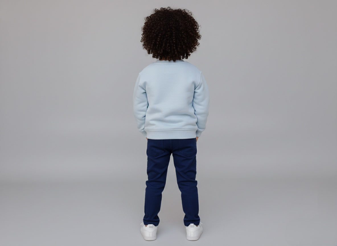 Child wearing a light blue sweatshirt and dark blue pants on a plain background