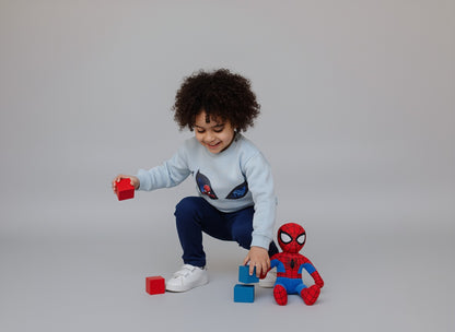 Child playing with toys including a Spider-Man figure on a plain background