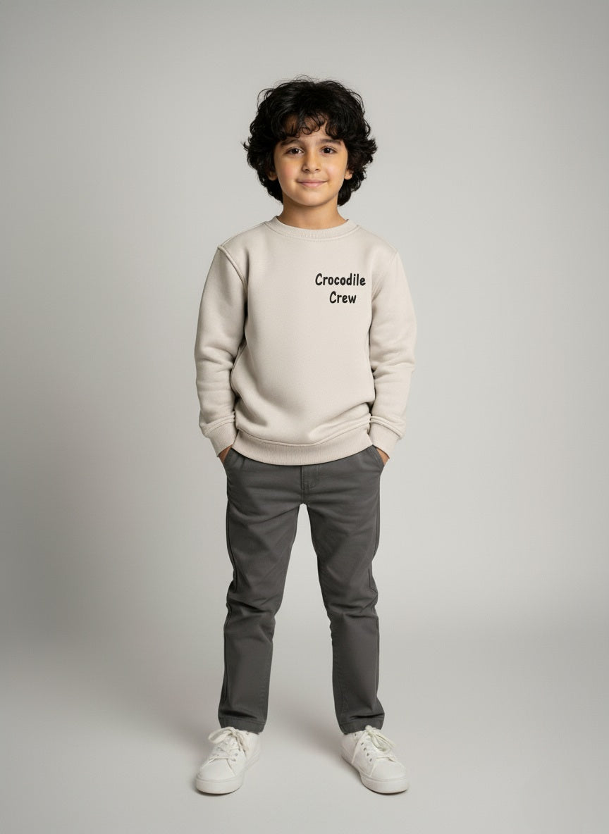 Child wearing a Gray sweater with text and gray pants on a plain background