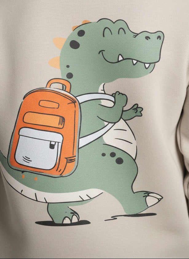 A child wearing a beige sweatshirt with a cartoon crocodile design on the back.