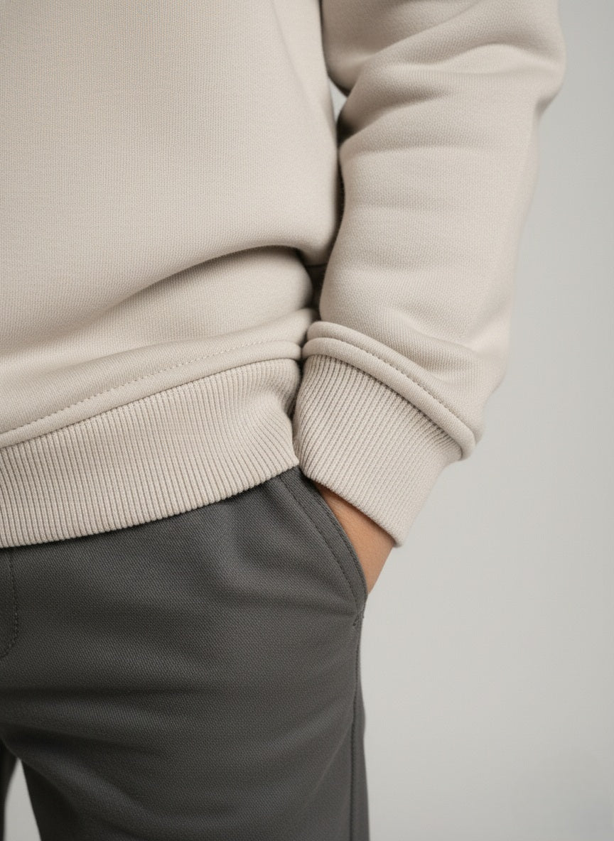 Close-up of a child wearing a gray sweater and gray pants on a light gray background