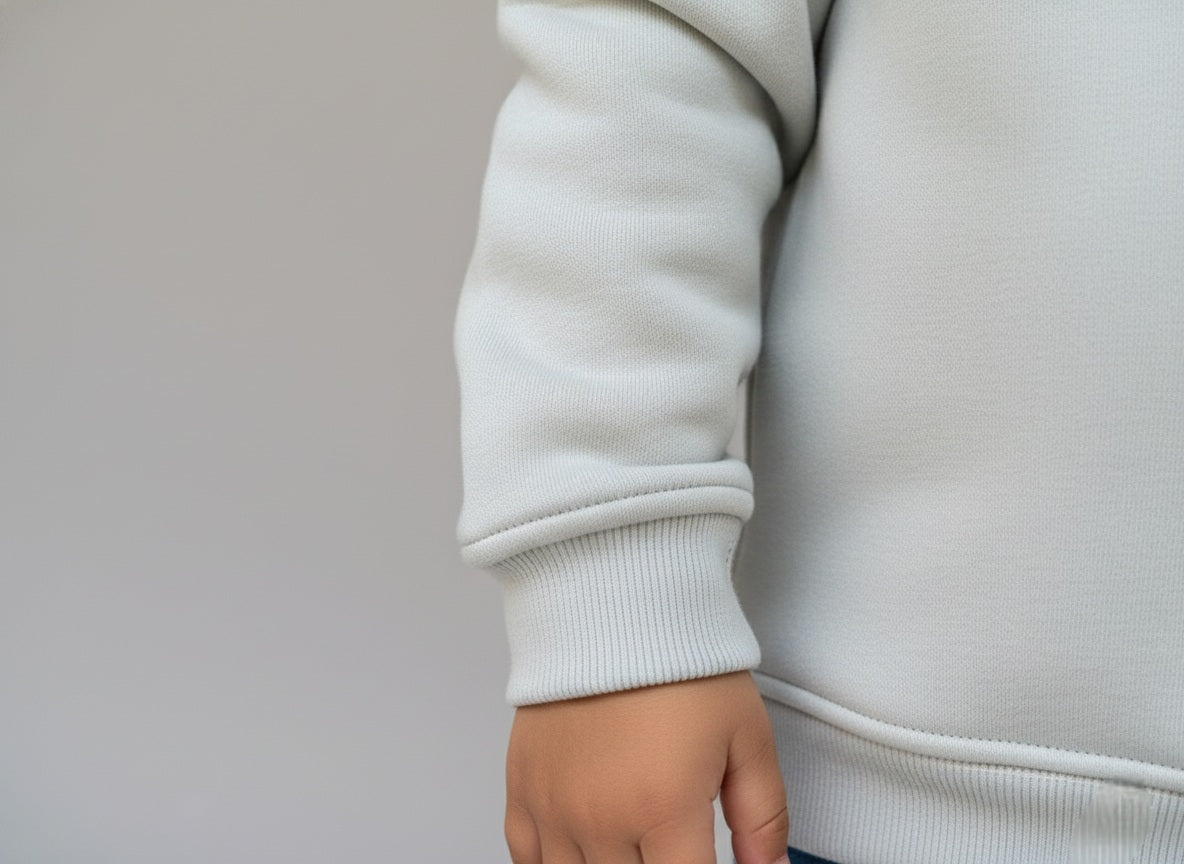 Close-up of a light gray sweatshirt sleeve and hand on a neutral background