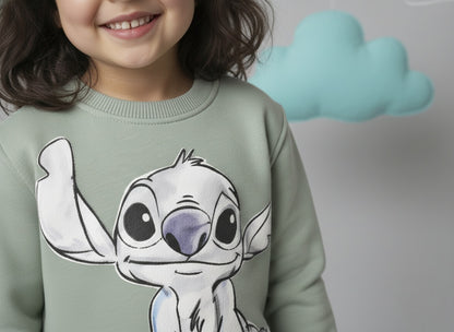 A girl wearing a mint green sweatshirt with a cute stitch design, standing against a plain background.