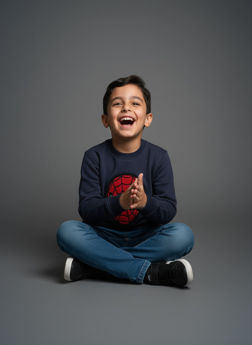 Child sitting on a gray background wearing a navy blue sweatshirt with a Spider-Man logo- Zoonikid