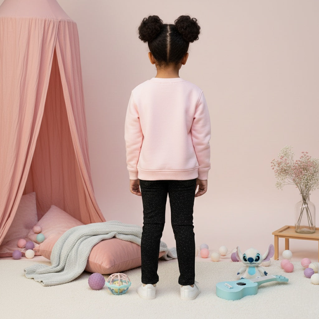 Child wearing a pink sweatshirt in a playroom with toys and a pink canopy.