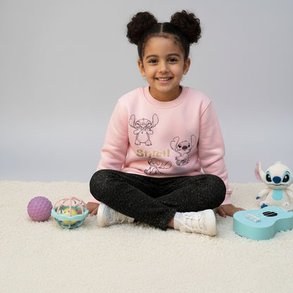 Child wearing a pink 'Stitch' sweatshirt with toys on a light gray background